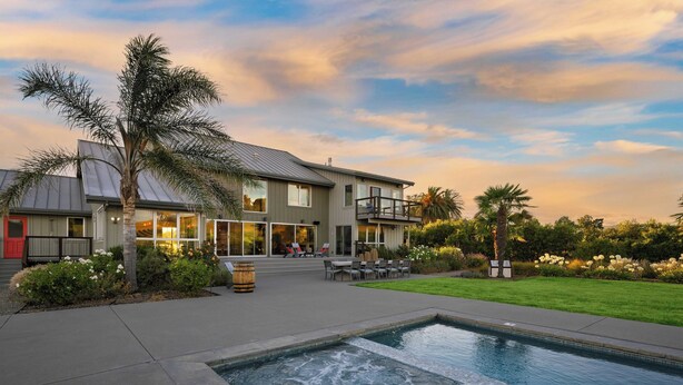 A modern two-story house with a swimming pool, outdoor seating, and a well-maintained garden.