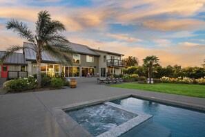 Una casa moderna de dos pisos con piscina, mobiliario exterior y un jardín bien cuidado.