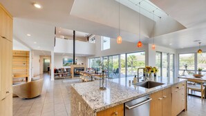 A modern kitchen with a large island, wooden cabinets, and a stainless steel dishwasher.