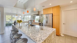 A modern kitchen with a large island, stainless steel appliances, and pendant lighting.