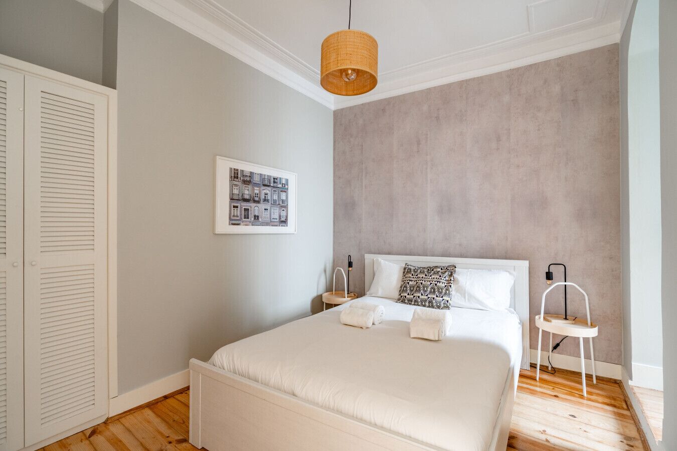 Une chambre à coucher comprenant un lit, une table de chevet, une chaise, une lampe suspendue et une armoire.