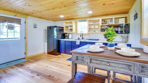 Een keuken met houten plafond, een koelkast, een spoelbak en een eettafel met borden.