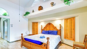 A spacious bedroom with a wooden bed, a large window with shutters, and a ceiling fan. - Pool & Dock! Canal-Front Port Charlotte Home (Port Charlotte)