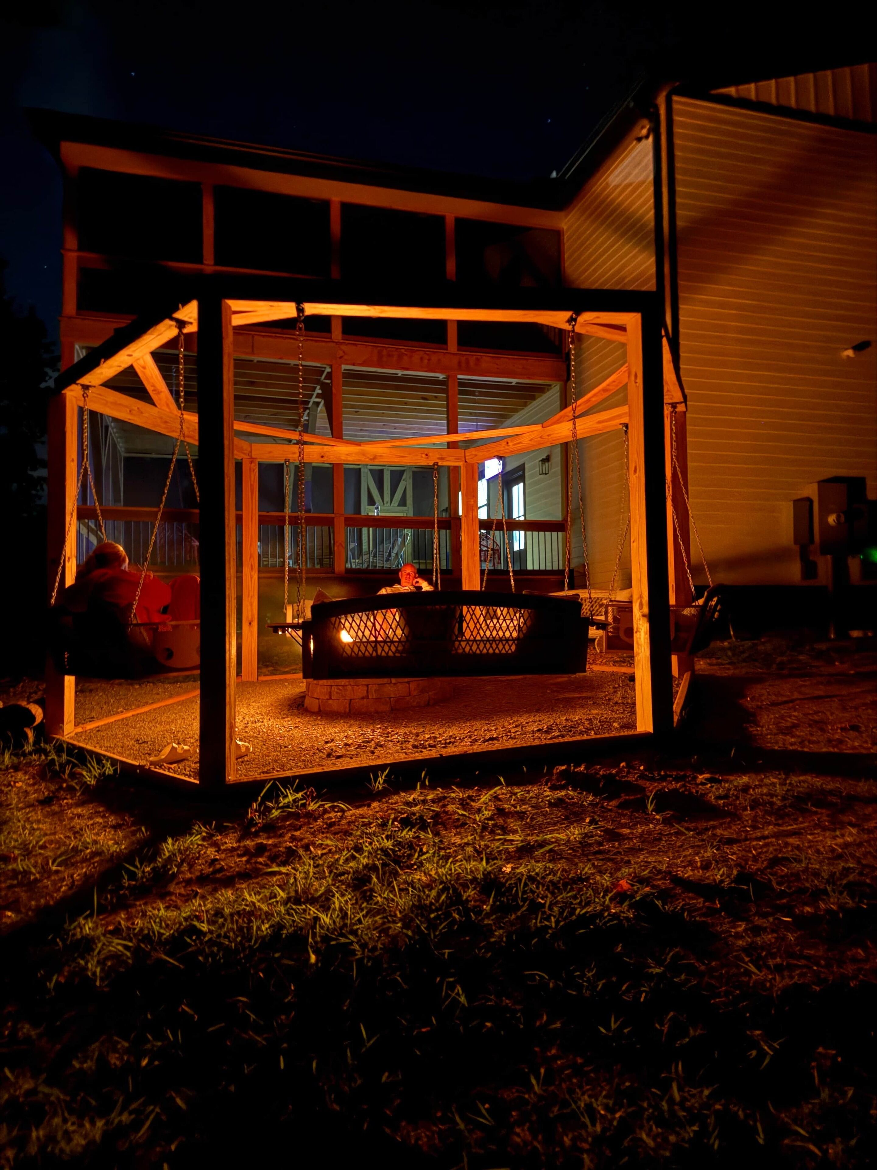 Eine Holzhütte mit Glasveranda, Feuerstelle und Sitzbereich.