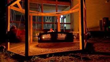 Eine Holzhütte mit Glasveranda, Feuerstelle und Sitzbereich.