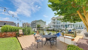 A wooden deck with a table and chairs, overlooking a marina with boats and buildings in the background. - < 1 Mi to Boardwalk! Family Getaway in Ocean City (Ocean City)