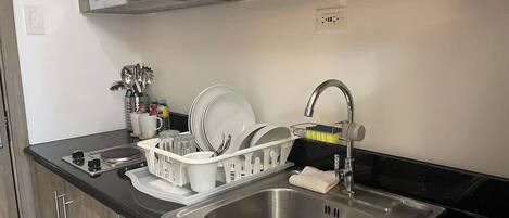 A modern kitchen with a stainless steel sink, a dish drying rack, and wooden cabinets.