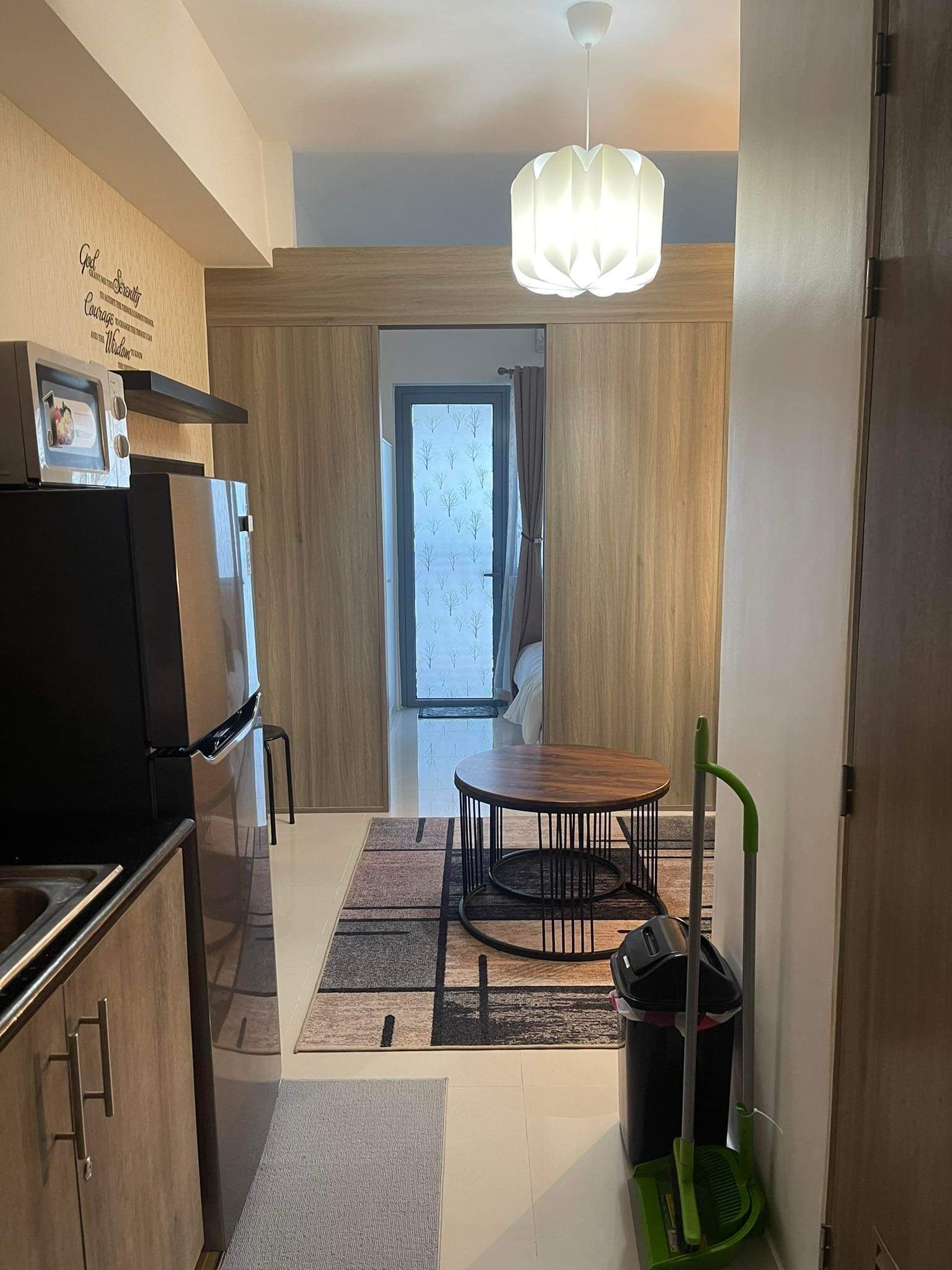 Una cocina moderna con un refrigerador empotrado, una mesa de comedor con sillas y una lámpara colgante.