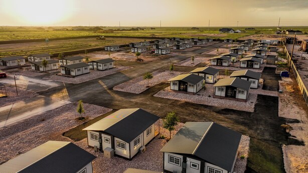A residential area with multiple small houses arranged in rows, surrounded by gravel and greenery. - Iron Horse Living - 1 Bed Studio (Odessa)