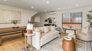 A modern living room with a sofa, coffee table, and a large rug. - Modern 5bdr, Mins to Sunset Cliffs & Ocean Beach Point View Luxe by Avantstay (San Diego)