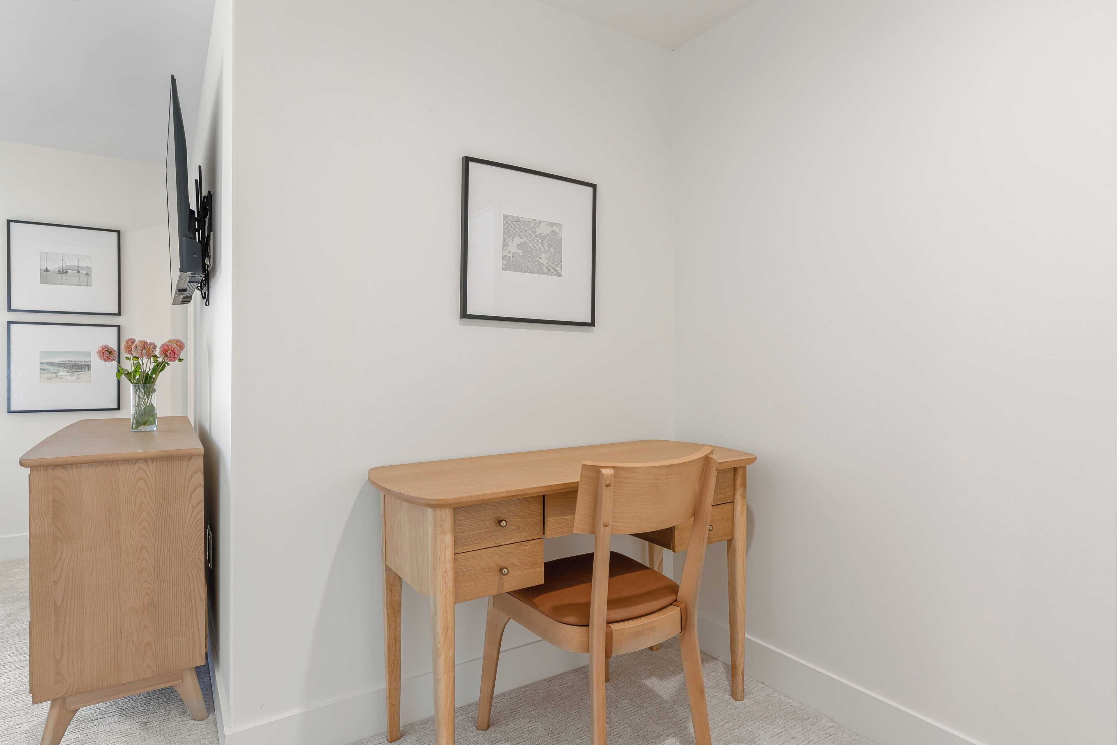 Habitació petita i acollidora, amb escriptori de fusta, una cadira, un armari petit i dos quadres al mur.