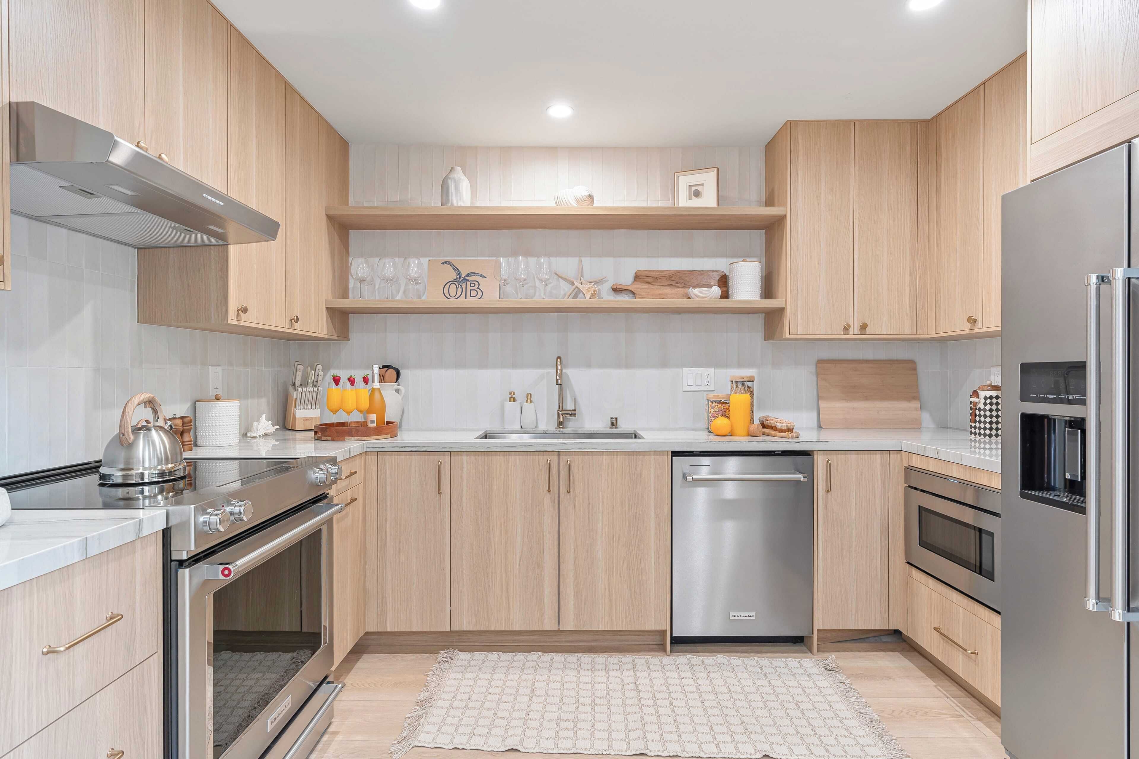 Une cuisine moderne avec des meubles en bois, des appareils électroménagers en acier inoxydable et un dosseret de carrelage blanc.