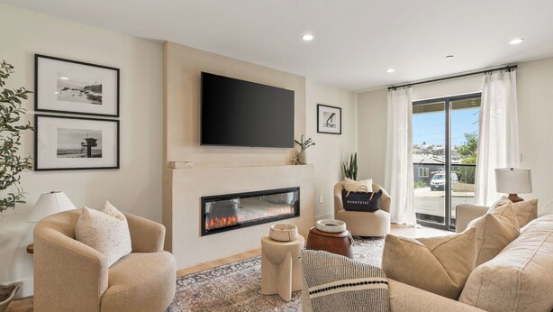 A modern living room with a fireplace, comfortable seating, and a large window with a view. - Modern 5bdr, Mins to Sunset Cliffs & Ocean Beach Point View Luxe by Avantstay (San Diego)