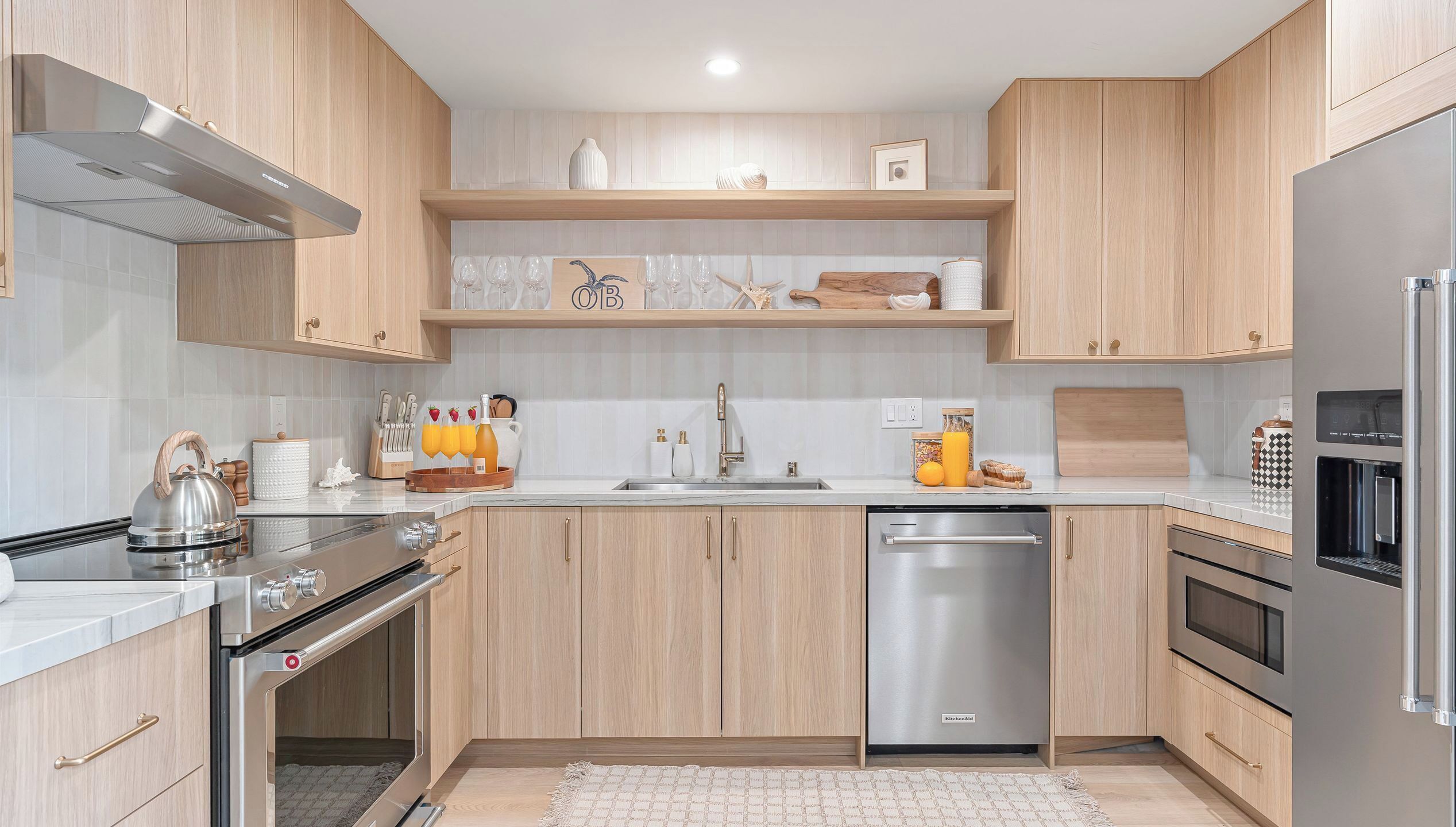 Une cuisine moderne avec des meubles en bois, un lave-vaisselle en acier inoxydable et un four encastré.