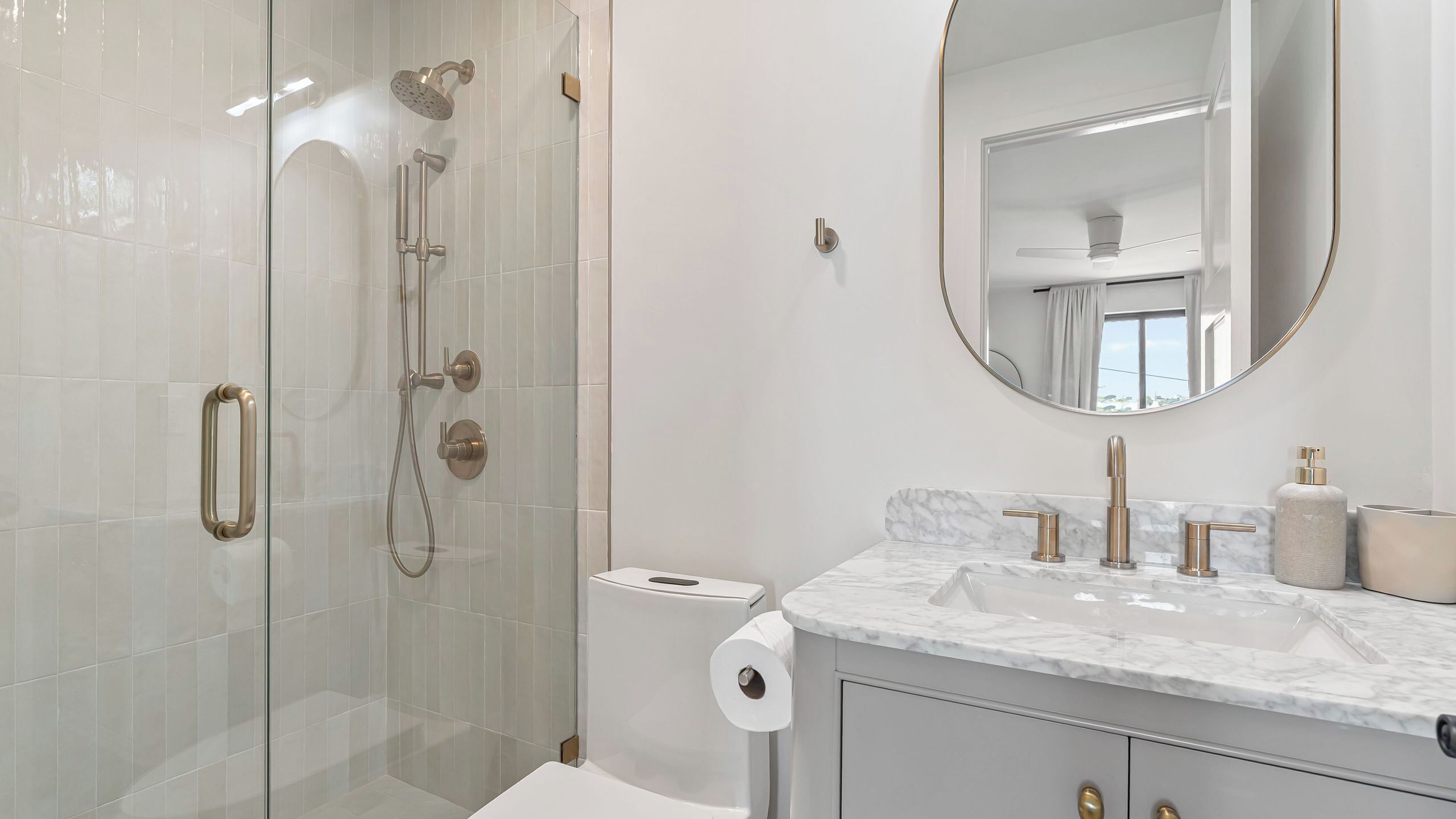 A modern bathroom with a glass-enclosed shower, a marble sink, and a large mirror.