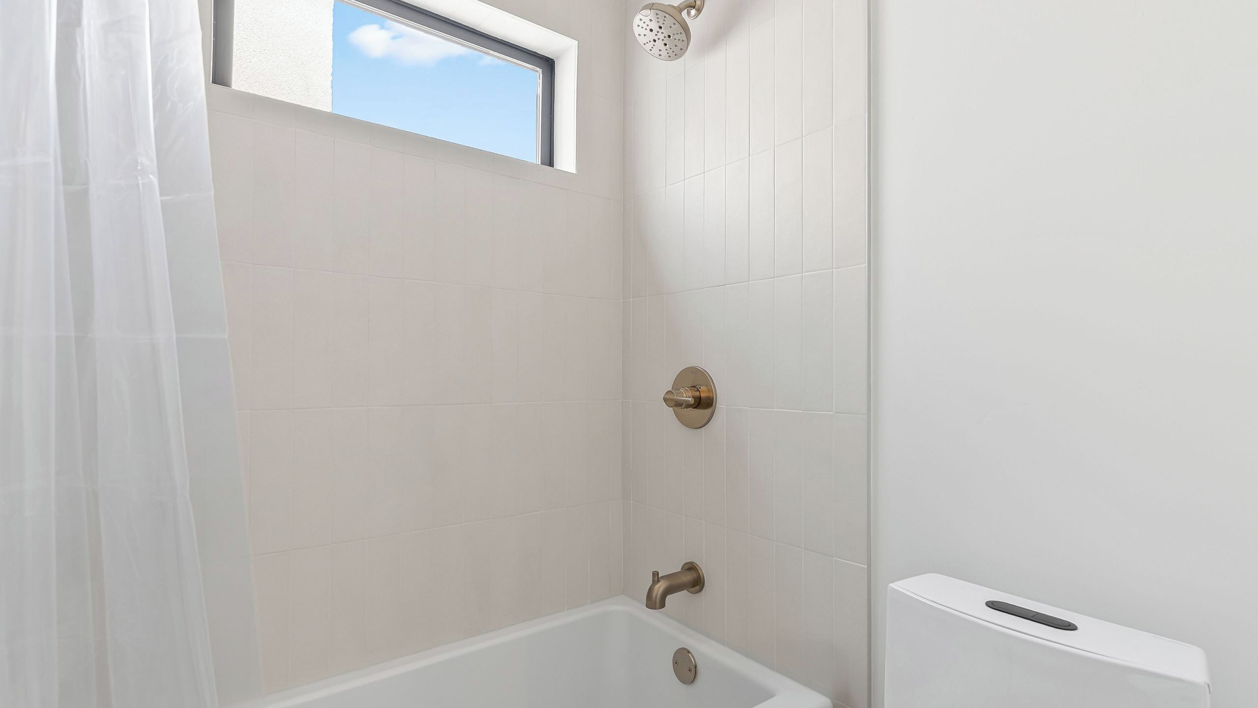 A bathroom with a bathtub, a showerhead, and a window.