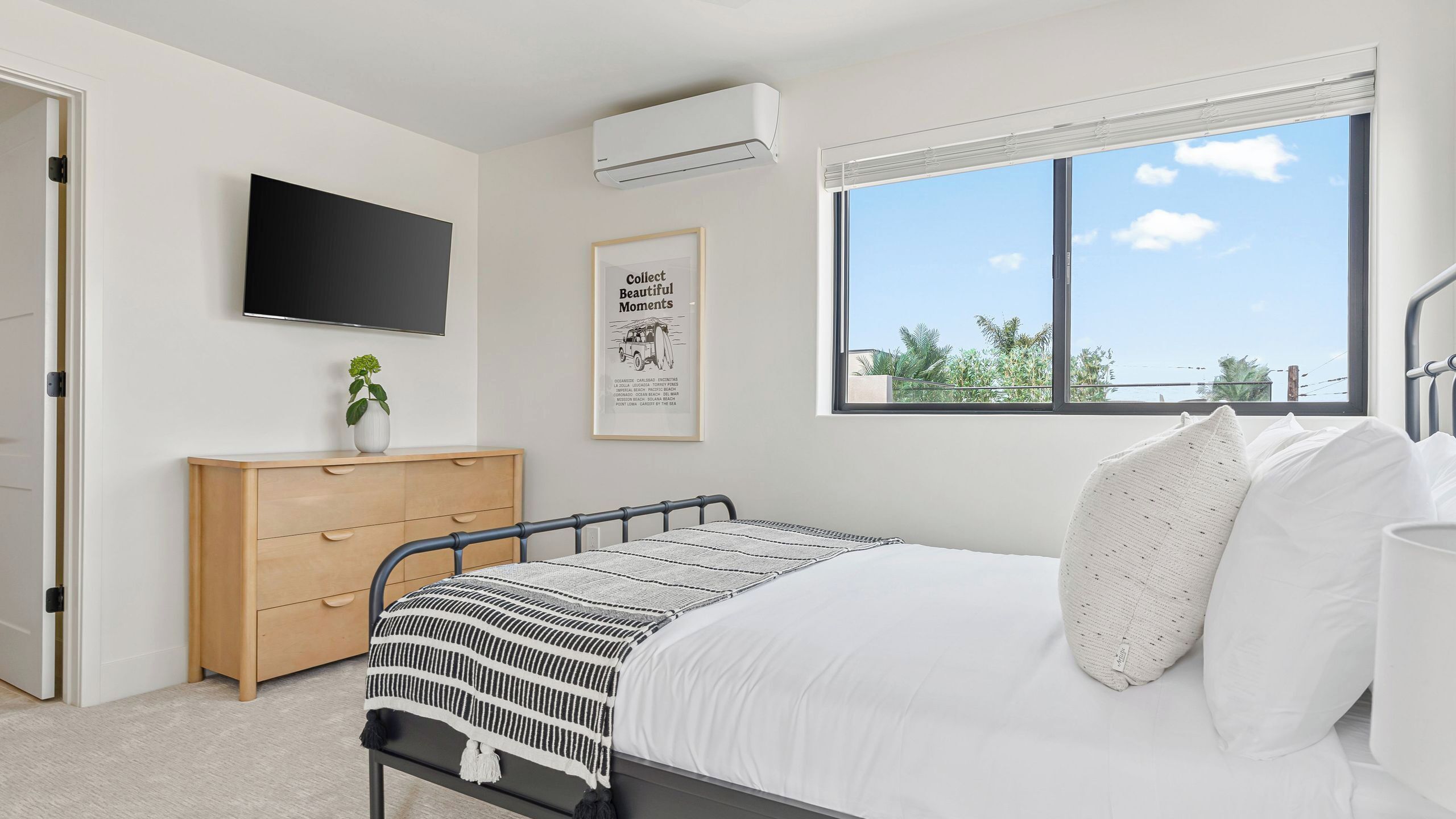 Ein Schlafzimmer mit Bett, Fernseher, Kommode, Fenster mit Blick und Klimaanlage.