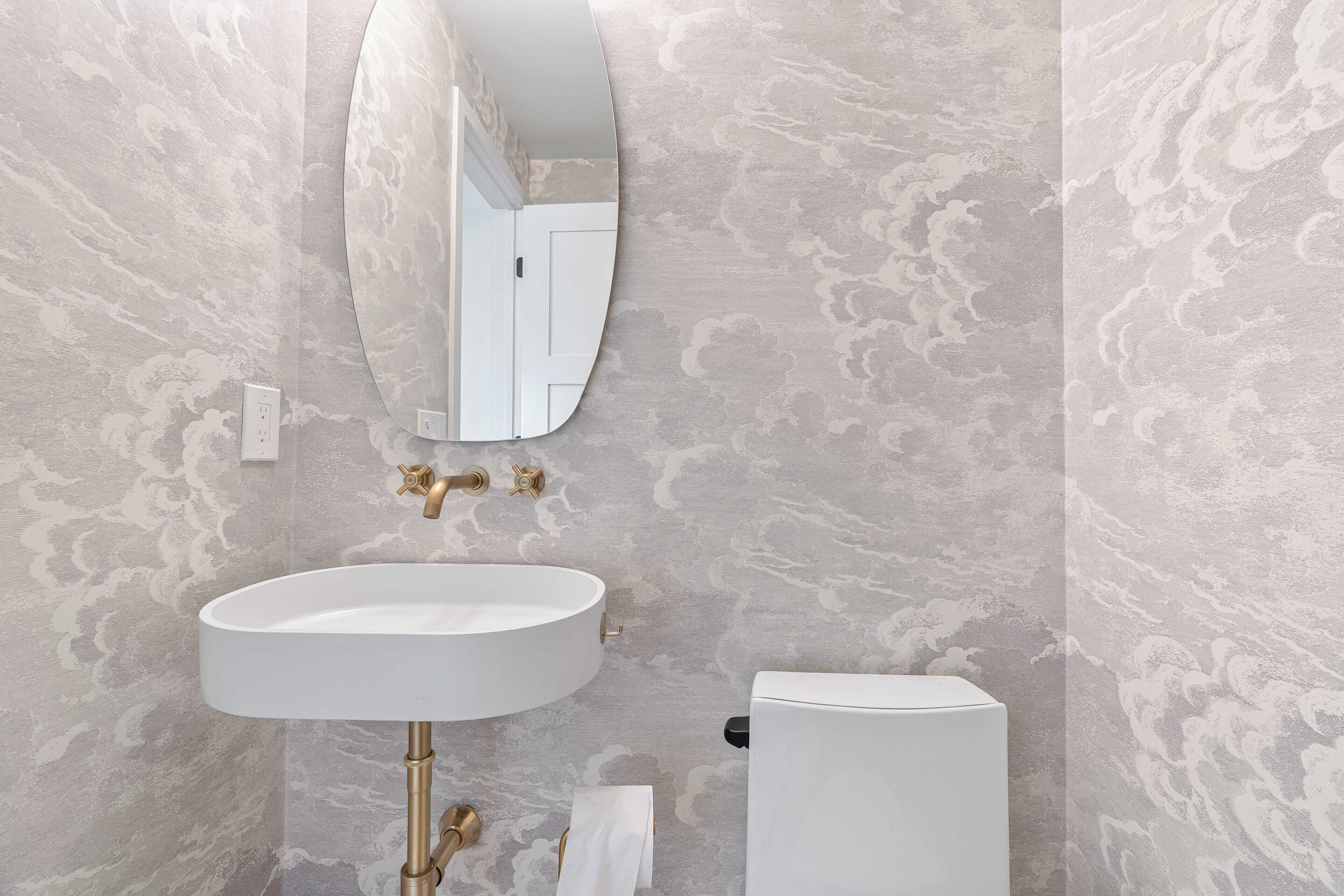 A bathroom with a white sink, gold fixtures, and a toilet.