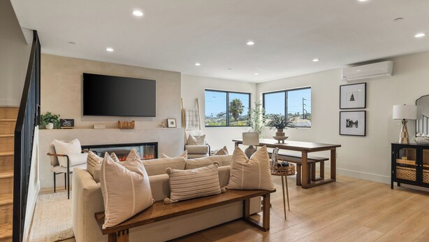 A living room with a fireplace, a sofa, a coffee table, a TV, and a staircase.