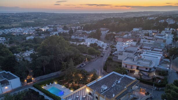Vue aérienne d’un quartier résidentiel, où l’on aperçoit un immeuble remarquable, doté d’une piscine sur le toit et d’un espace de détente extérieur.