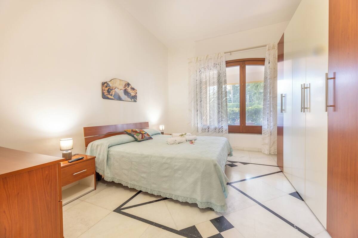 A bedroom with a bed, bedside tables, a desk, and a wardrobe.