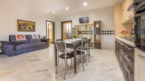 Une cuisine moderne avec un coin repas, un sol en marbre et un canapé agrémenté de coussins décoratifs.