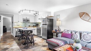 Una cucina moderna con isola centrale, elettrodomestici in acciaio inossidabile e zona pranzo con tavolo e sedie.