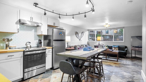 A modern kitchen with a central island, stainless steel appliances, and a stone tile floor. - 2mins to Historic Main Street + Deer Valley Ski Lift Alpine Ember by Avantstay (Park City)