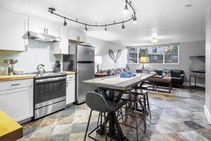 A modern kitchen with a central island, stainless steel appliances, and a stone tile floor. - 2mins to Historic Main Street + Deer Valley Ski Lift Alpine Ember by Avantstay (Park City)