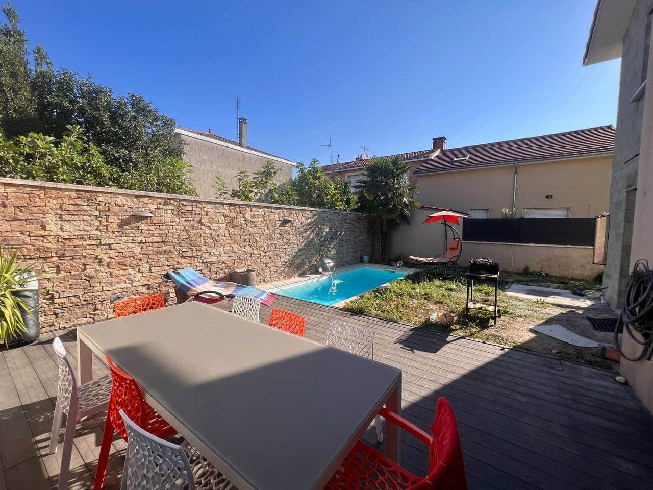 A backyard with a swimming pool, a table, and chairs.