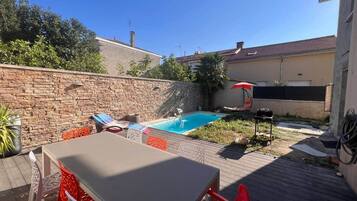 A backyard with a swimming pool, a table, and chairs.