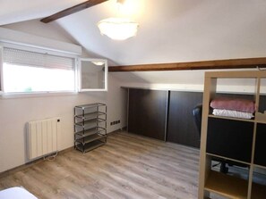 A room with a sloped ceiling, a radiator, a metal shelf unit, a desk with a chair, and a wardrobe. - Modern and spacious house with a swimming pool (Villeurbanne)