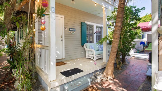A porch with a white railing, a welcome sign, and a bench.