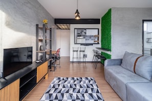 A modern living room with a flat-screen TV, wooden entertainment unit, and a grey sofa.
