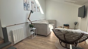 A modern, well-lit room with a skylight, a bed, a chair, and a radiator. - La Calypso de Paimpol (Paimpol)