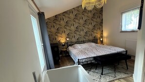 A modern bathroom with a freestanding bathtub, a shower, and a window with curtains. - La Calypso de Paimpol (Paimpol)