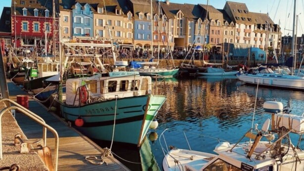 A marina with boats docked, wooden walkways, and colorful buildings in the background. - La Calypso de Paimpol (Paimpol)