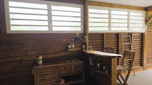 A rustic wooden room with a bar area, a chair, and a ladder. - Ti Kaz Romalex (Deshaies)
