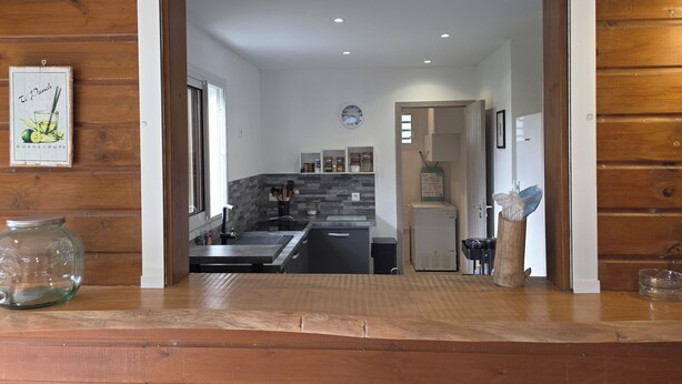 A modern kitchen with a central island, a refrigerator, and a window. - Ti Kaz Romalex (Deshaies)