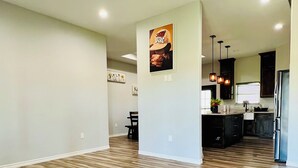 A spacious living area with hardwood flooring, a ceiling fan, and a kitchen area with modern appliances.