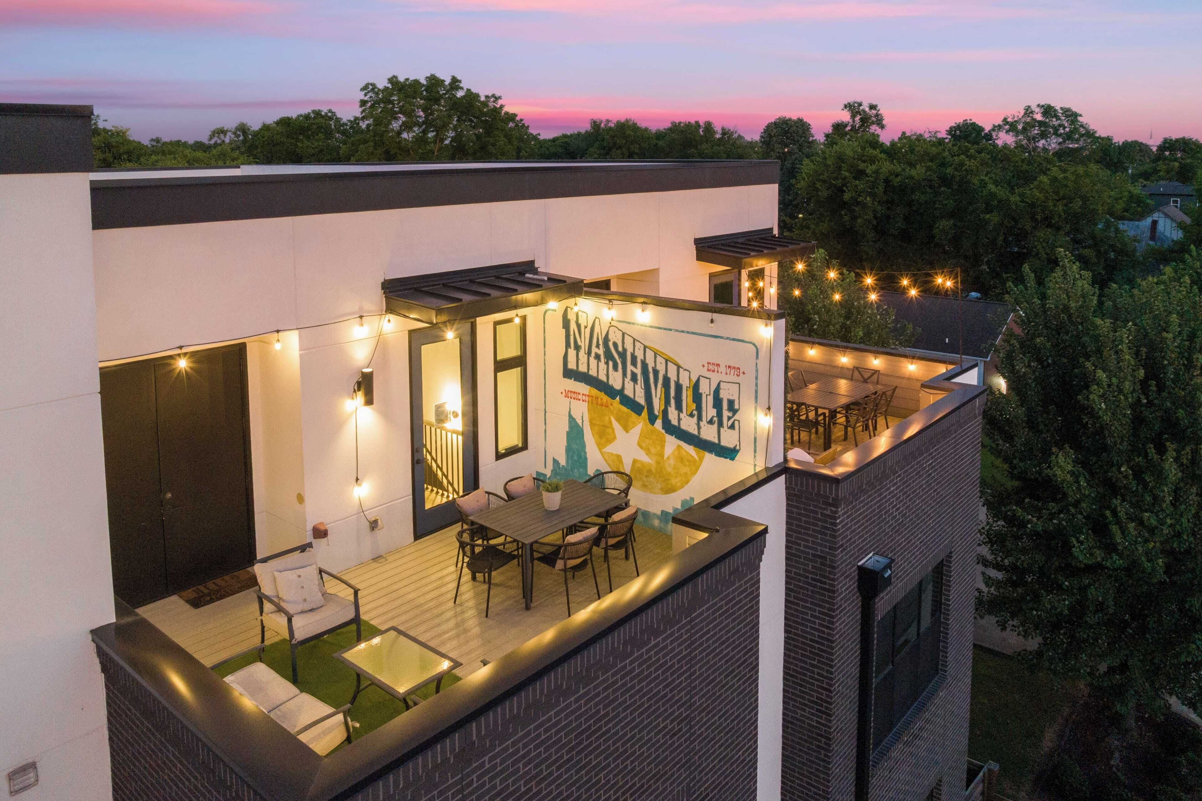 A rooftop patio with a dining area, outdoor lighting, and a mural of Nashville.