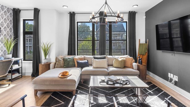 A modern living room with a sectional sofa, a coffee table, and a large TV on the wall. - Skyline Soundhouse by Avantstay Rooftop Deck & Game Room Near East Nashville & Broadway (Nashville)