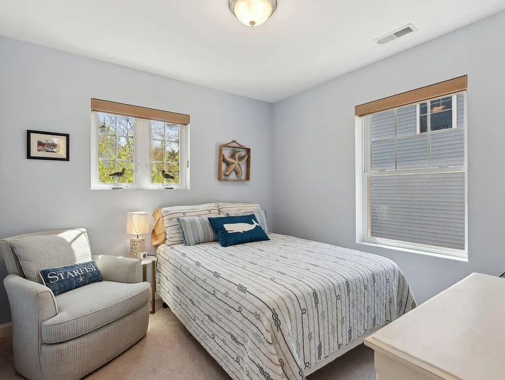 Un dormitorio con cama, una silla, una mesita de noche y una ventana.