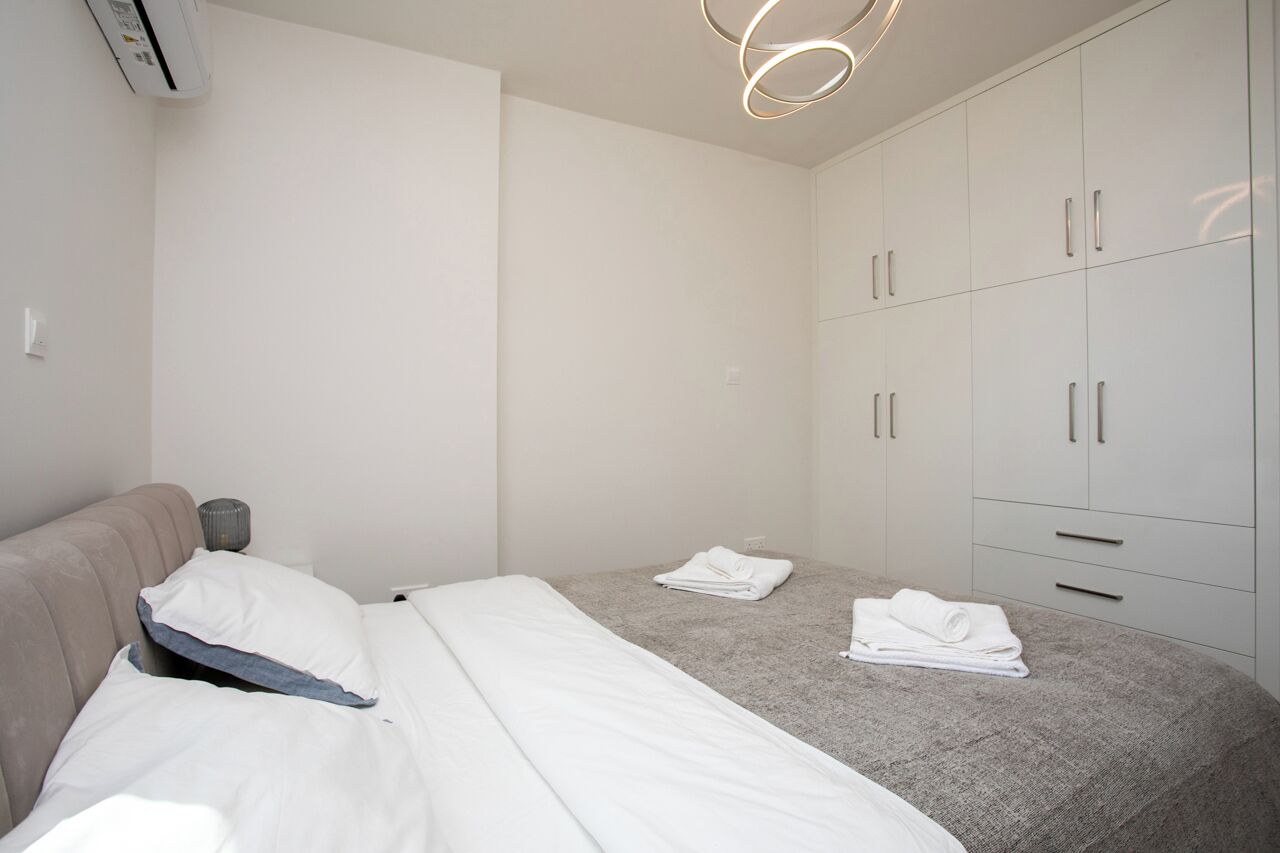 Ein Schlafzimmer mit Bett, Kleiderschrank und Deckenleuchte.