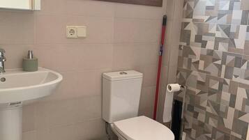 Une petite salle de bain avec des toilettes, un lavabo et une fenêtre.