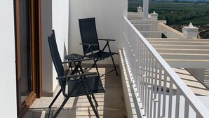 Een balkon met twee zwarte stoelen en een tafel, met uitzicht op een prachtig landschap.