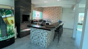 A modern kitchen with a central island, a built-in oven, and a large window. - Happy FAMILY (Parque Turistico Peruíbe)