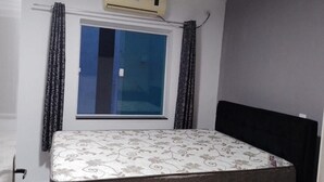 A small room with a bed, a window with curtains, and an air conditioning unit. - Happy FAMILY (Parque Turistico Peruíbe)