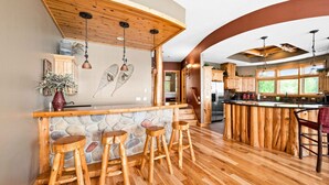 A kitchen with wooden bar stools, a stone countertop, and wooden cabinets. - Lakeview 5 bedroom Executive Suite (Two Harbors)