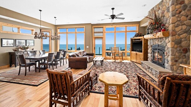A spacious living room with a stone fireplace, large windows, and a view of the ocean. - Lakeview 5 bedroom Executive Suite (Two Harbors)